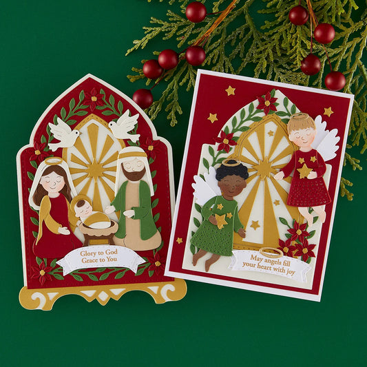Two red and gold Christmas greeting cards displayed on a dark green background with pine branches and red berries. One card shows a nativity scene with the text 'Glory to God Grace to You,' and the other shows angels with the text 'May angels fill your heart with joy.
