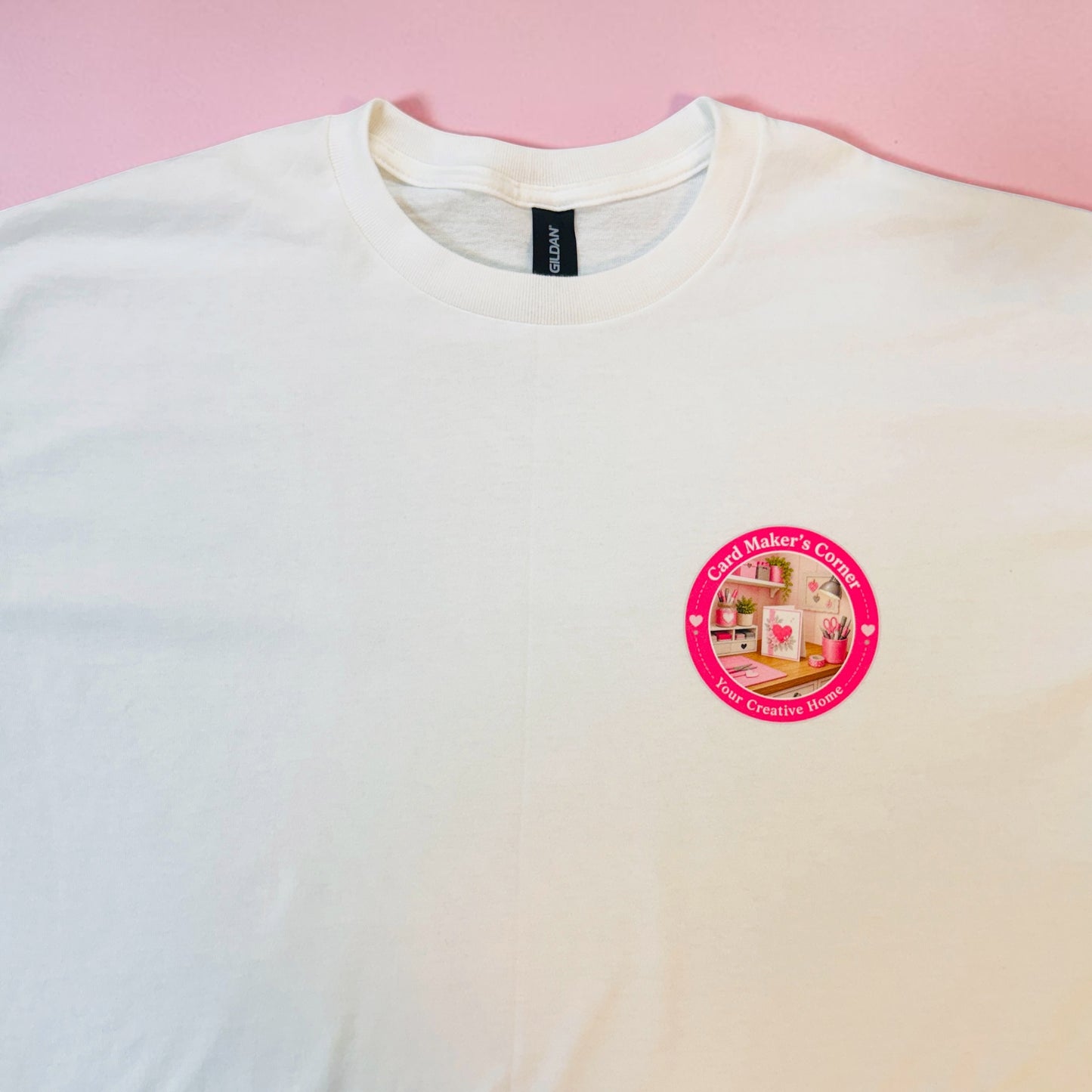 White t-shirt with a pink logo on a pink background