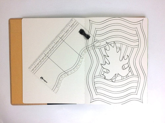 An open notebook or journal on a white background, showing a clear acrylic planner insert with printed lines and a black elastic closure. The right page has black line art illustrations.