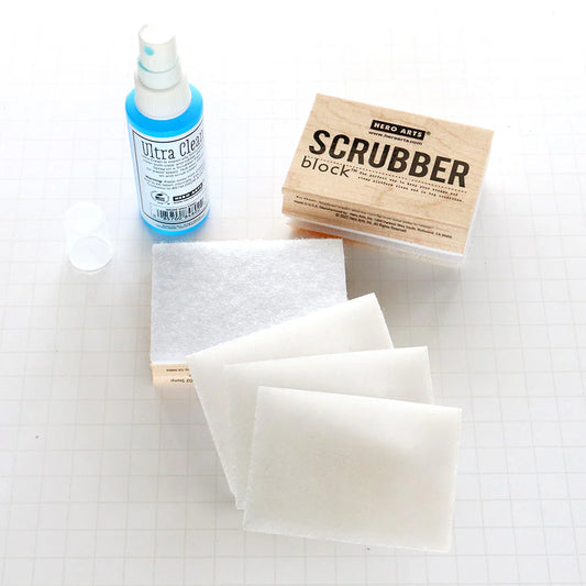 Cleaning supplies including a bottle of Ultra Clean, a scrubber block, and cleaning pads on a white surface.