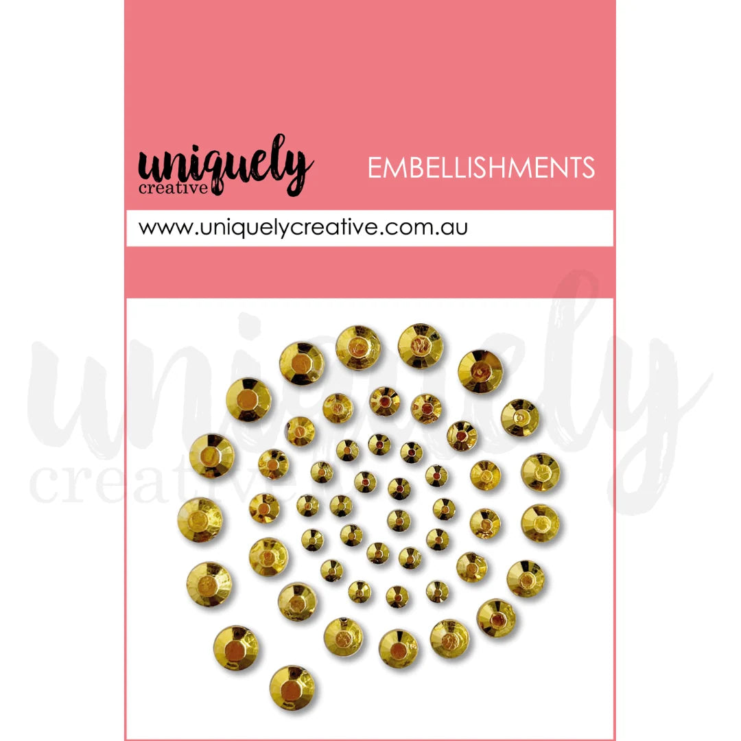 A package of Uniquely Creative embellishments, featuring a spiral arrangement of small round gold rhinestones on a white background with a pink header card.
