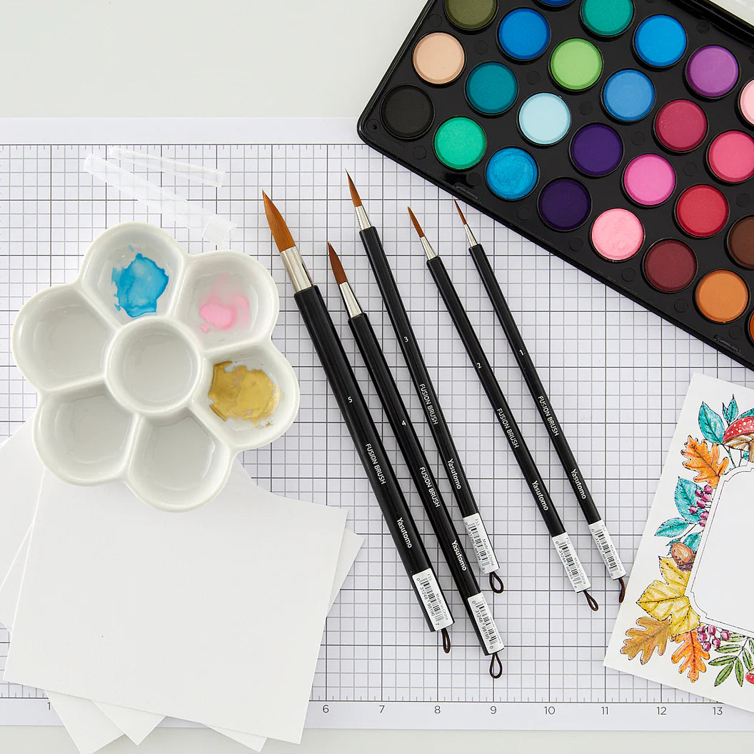 Yasutomo paintbrushes, a water color palette, and a floral design on grid paper.