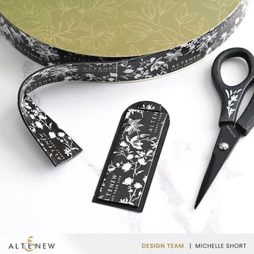 Decorative ribbon, scissors, and packaging with floral design on a white background.