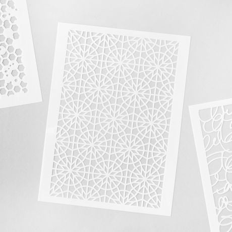 Set of white stencils with geometric patterns on a gray background