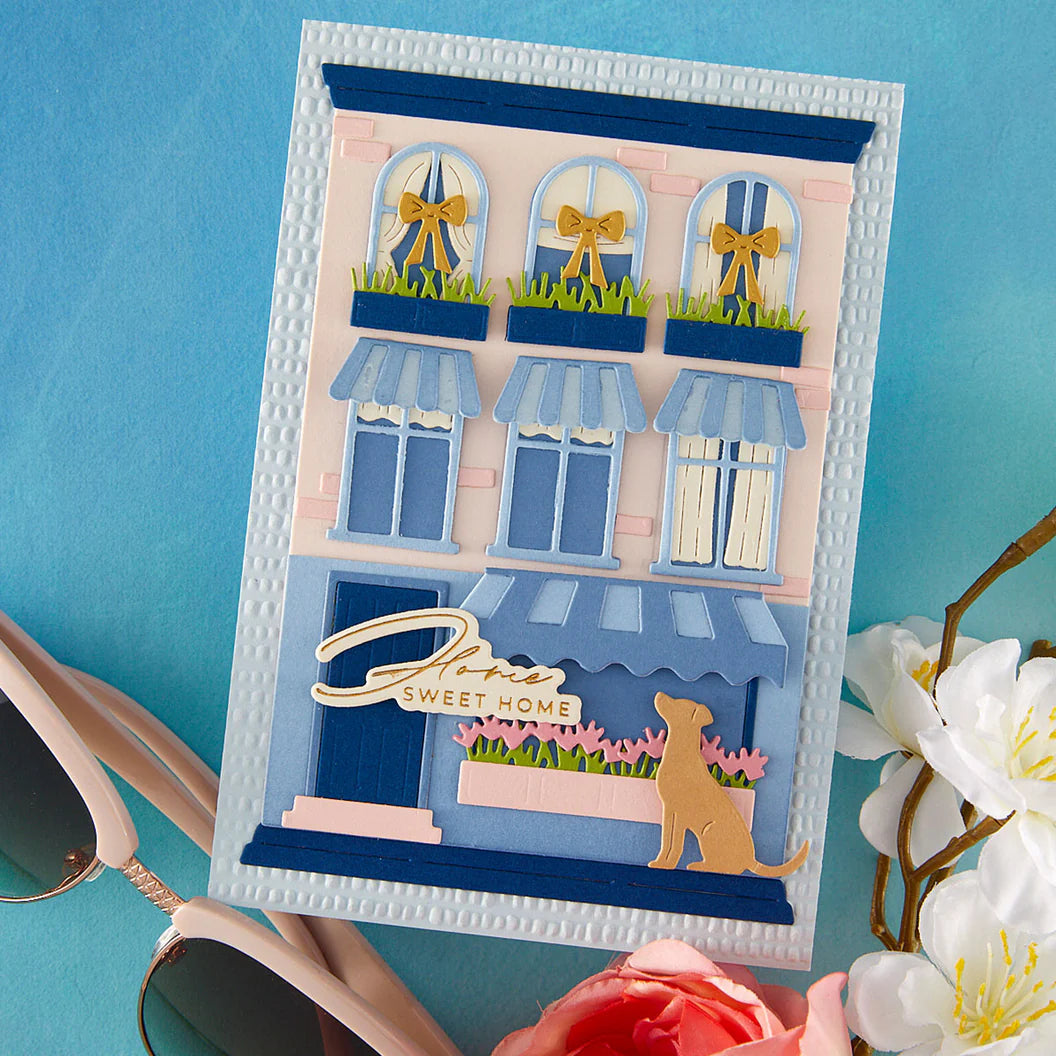 Handmade card with a decorative building design featuring windows and a dog, on a blue background.