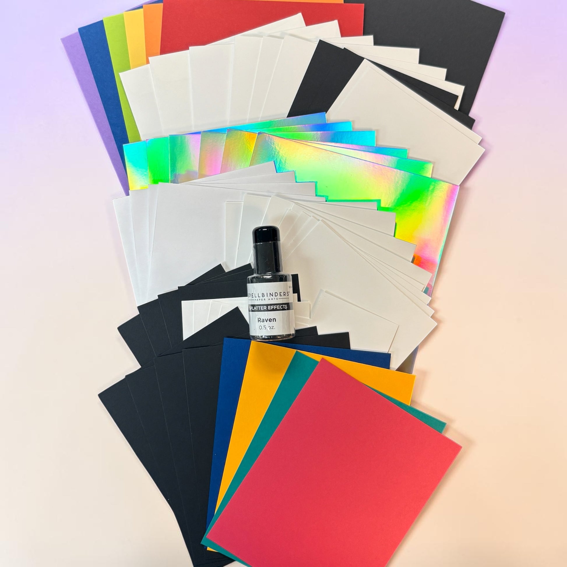 spread of rainbow colored paper with black and holographic paper on white background