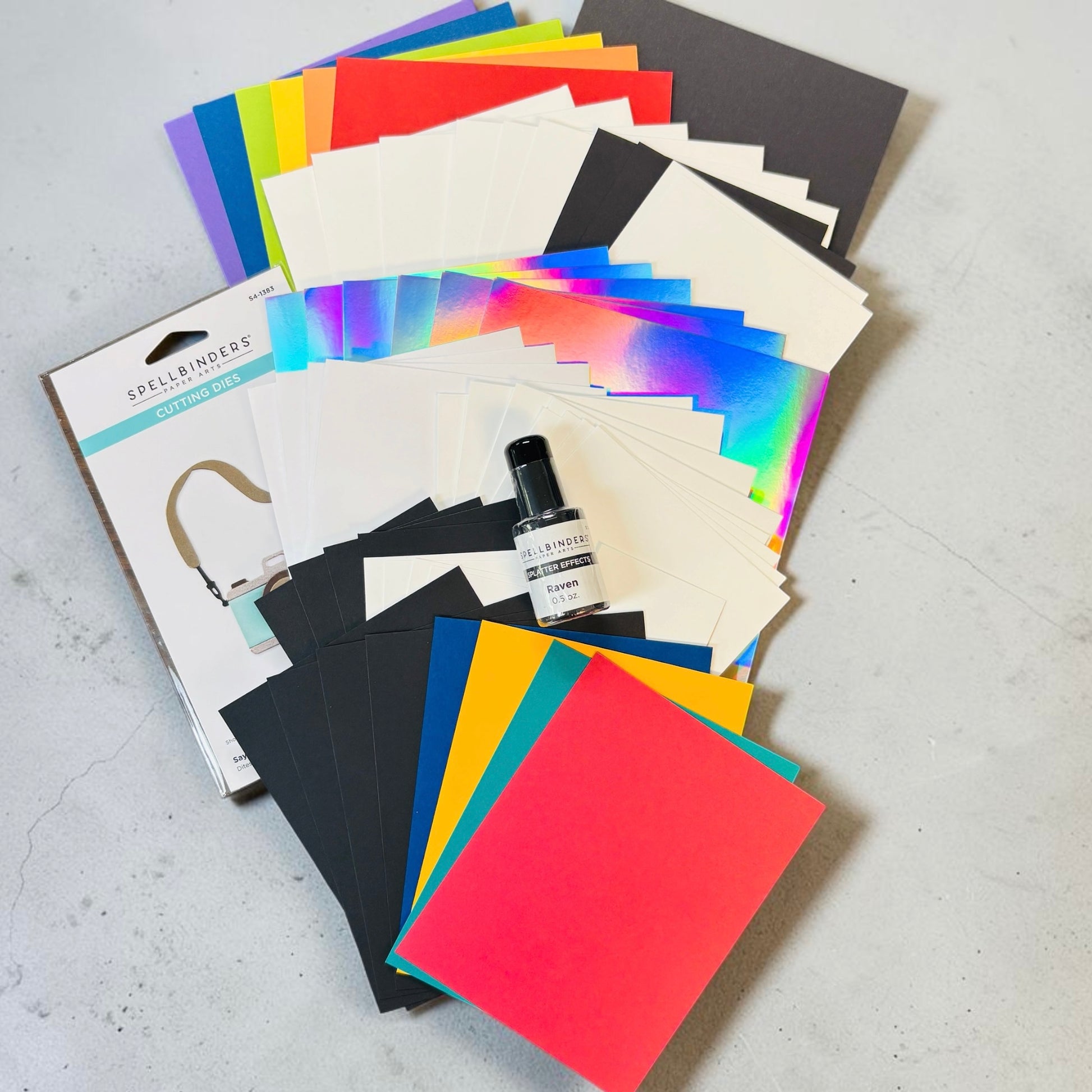 rainbow and holographic papers bottle of black spellbinders splatter effects with a black cap and image of camera dies in package