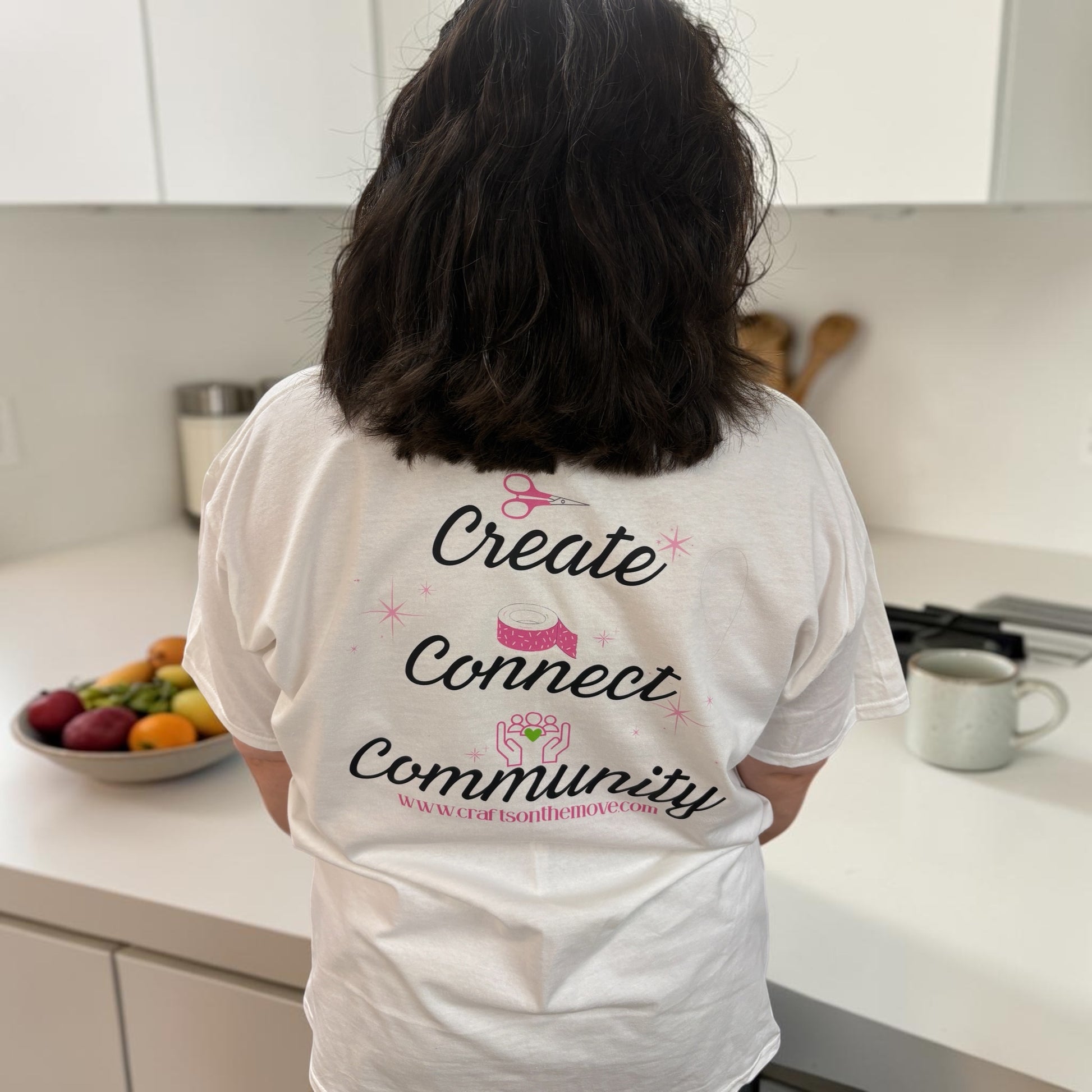 Person wearing a white t-shirt with text in a kitchen