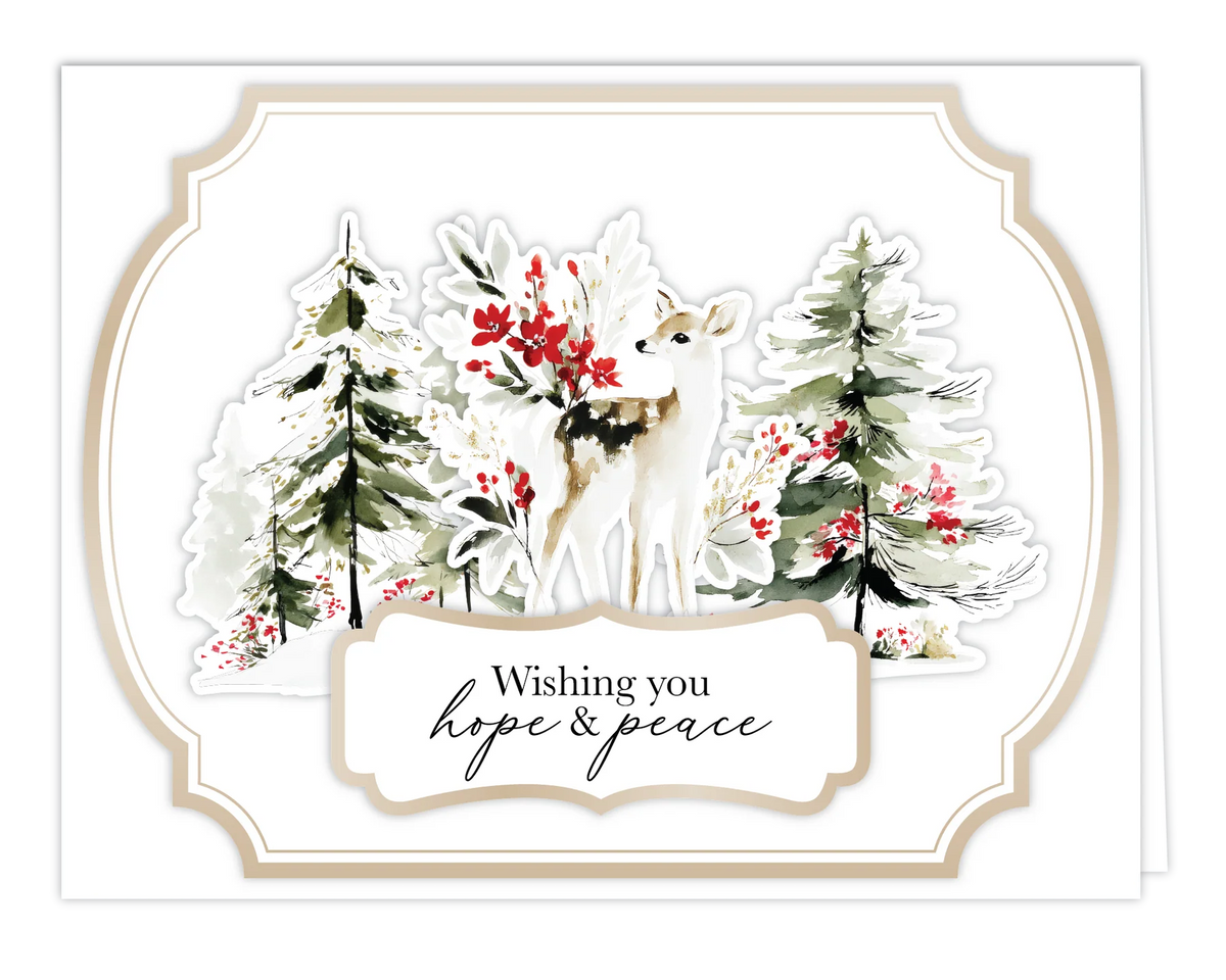 A square greeting card with a white border and a watercolor winter scene featuring a white deer among snowy trees and red berries. A white label at the bottom reads “Wishing you hope & peace.
