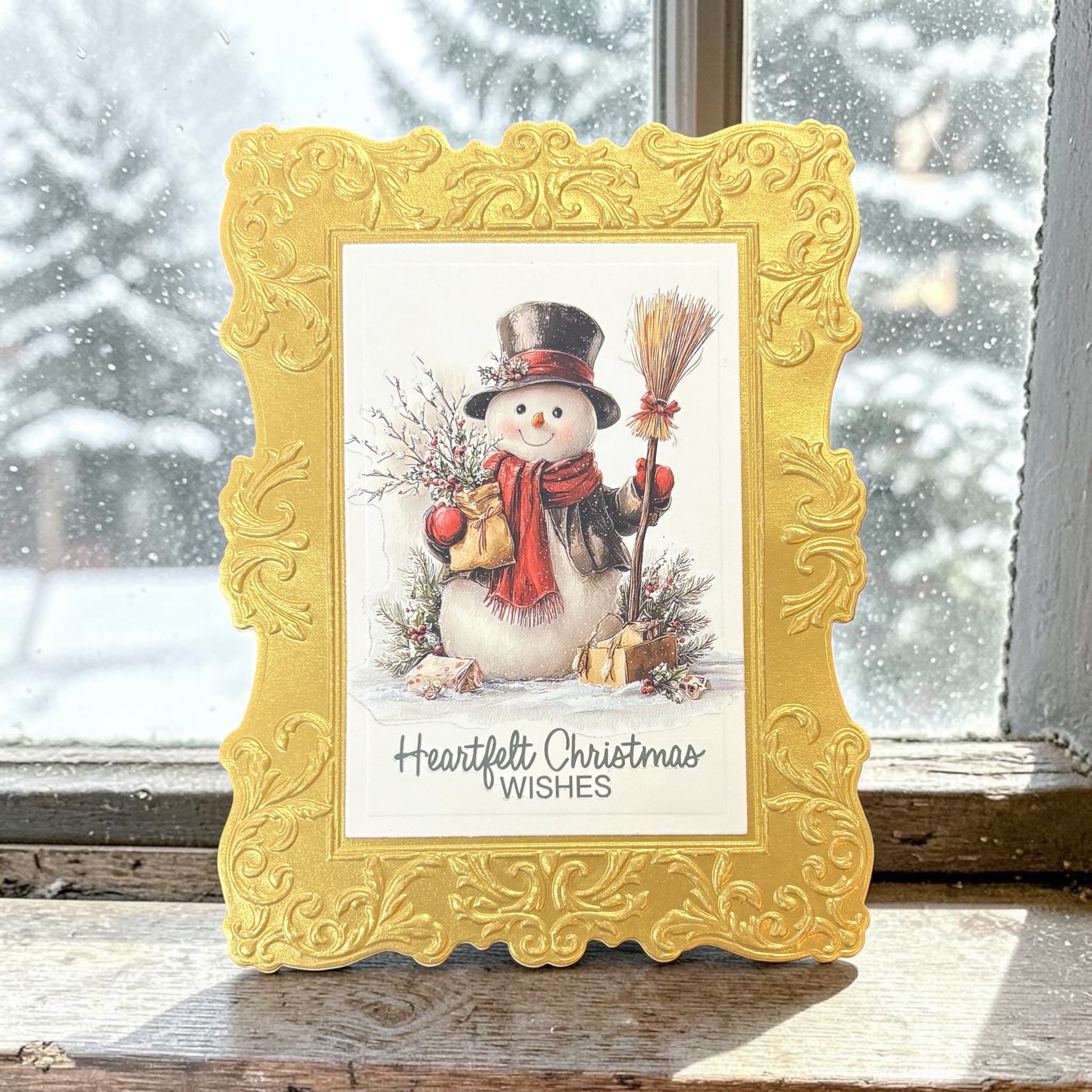 Decorative gold frame Christmas card featuring a snowman on a snowy background.