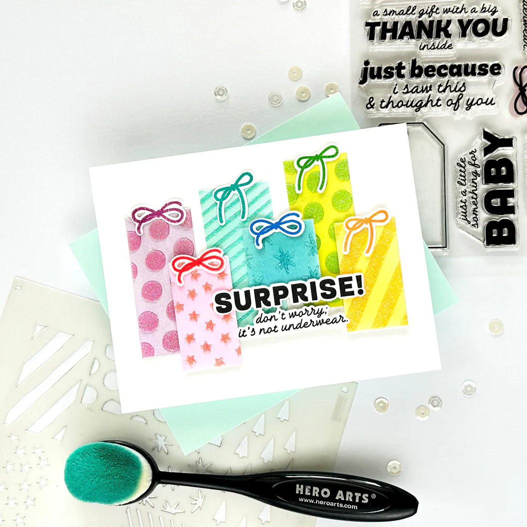 Colorful gift box card with 'Surprise!' text, surrounded by crafting tools on a light background.