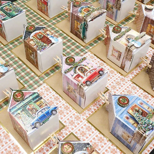 Collection of decorative boxes with house and car designs on a checkered tablecloth.