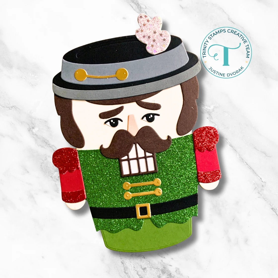 holiday themed take out coffee cup shaped card with a nutcracker on the front, trinity stamps logo on the side all on a white marble background