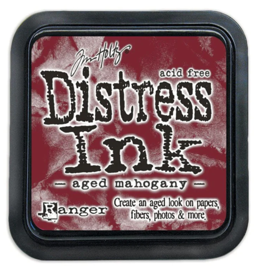 Distress Ink pad by Ranger with 'aged mahogany' color on a red and white distressed background.