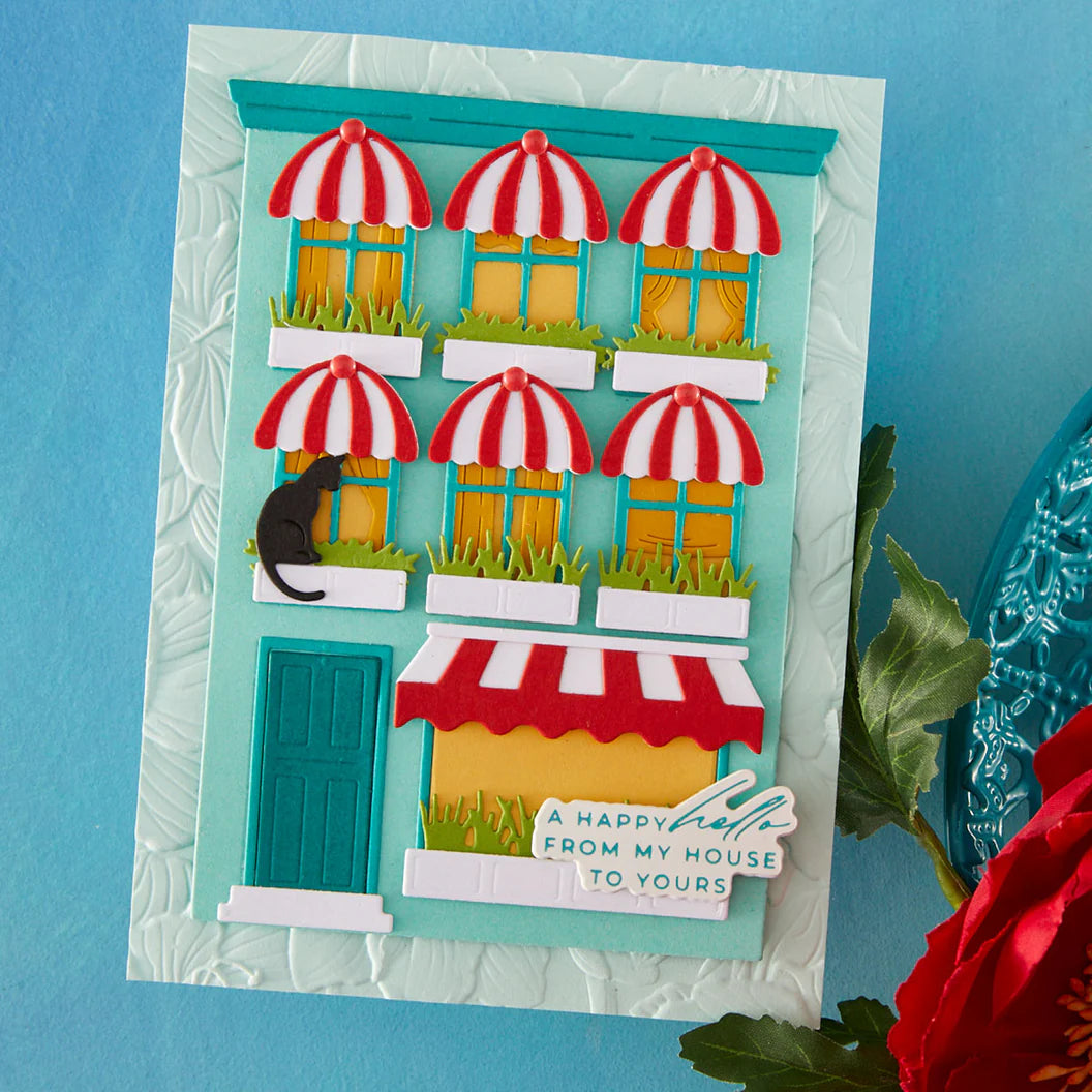 Handmade card with a colorful street scene and red flower on a blue background