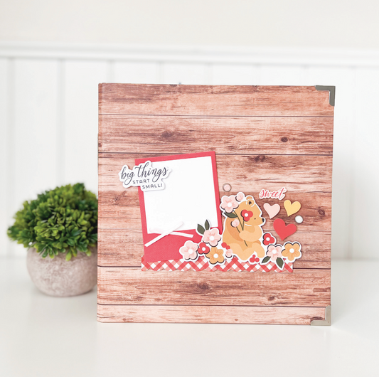 Wooden photo album with decorative cover featuring a teddy bear and hearts on a white background.