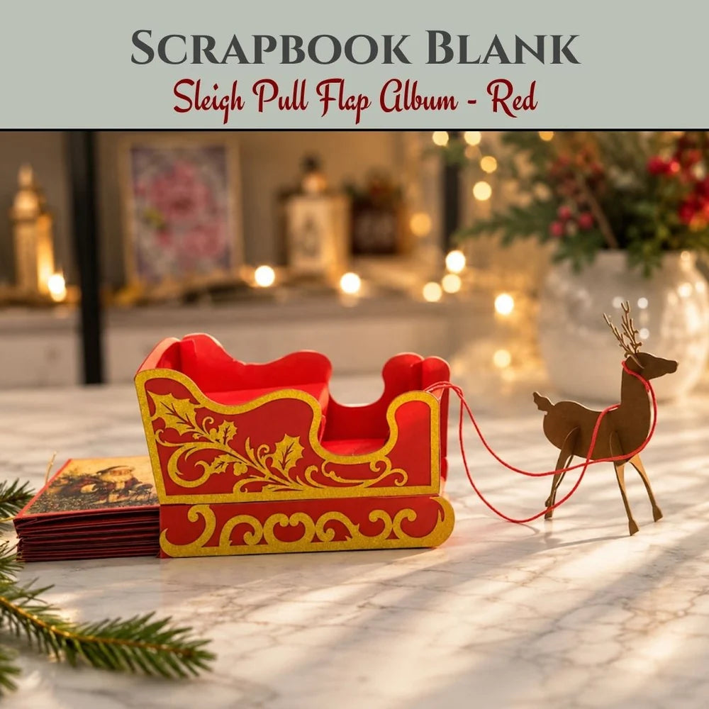 A Christmas-themed scrapbook blank set featuring a red and gold sleigh with a brown reindeer pull, styled on a marble surface with holiday lights and greenery in the background. Text at the top reads 'SCRAPBOOK BLANK' and 'Sleigh Pull Flap Album - Red'.