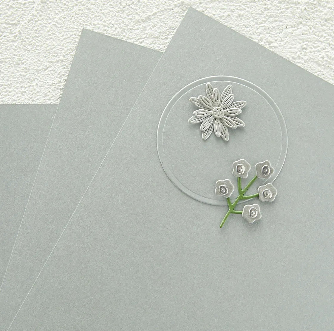 Brushed silver circle cardstock with floral design on a gray surface