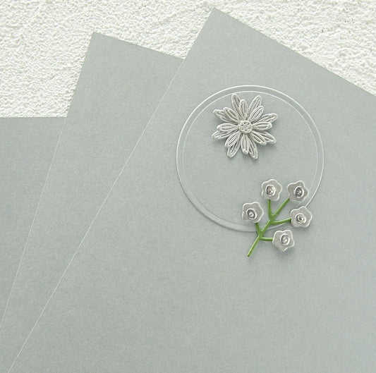 Brushed silver circle cardstock with floral design on a gray surface