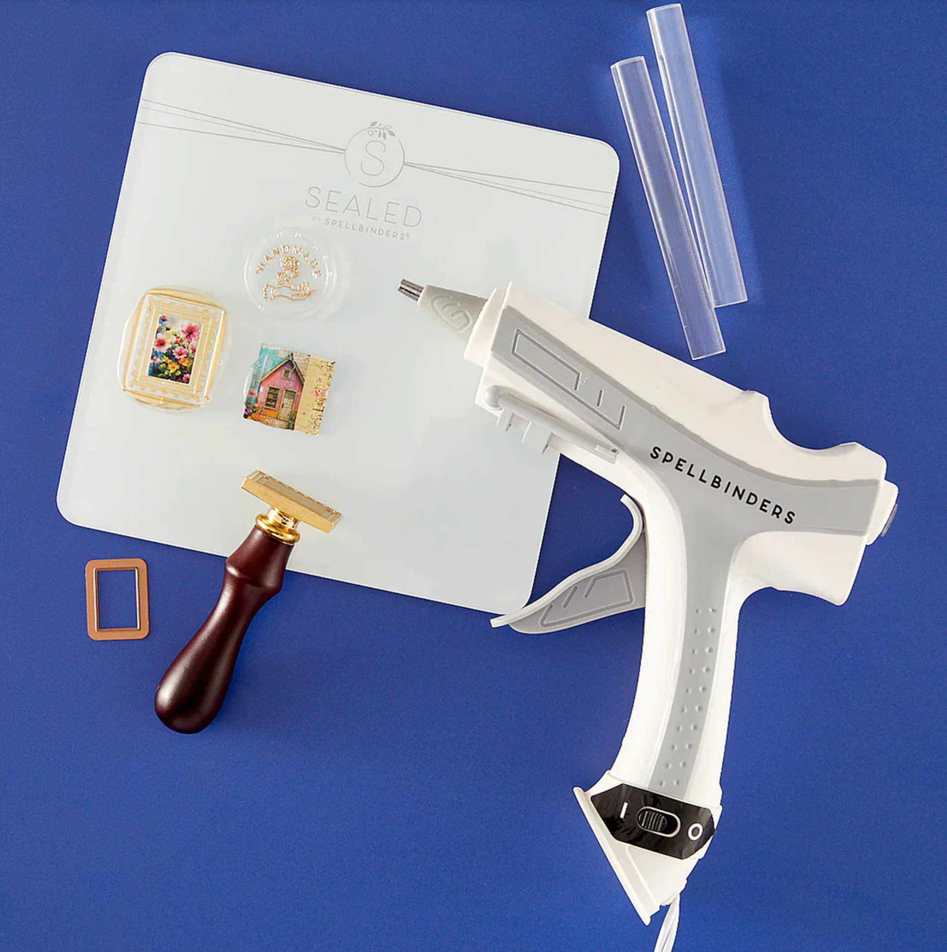 Spellbinders craft tool set with glue gun, die cutters, and other tools on a blue background