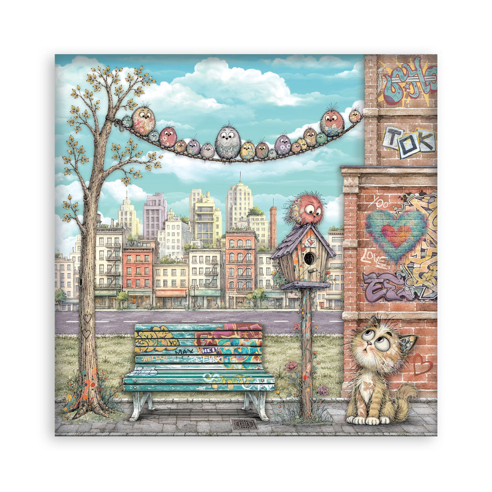 A square sheet of paper featuring a whimsical illustrated city street scene with a bench, graffiti-covered wall, tree, birdhouse, and a cat sitting in the foreground under a blue sky with clouds.