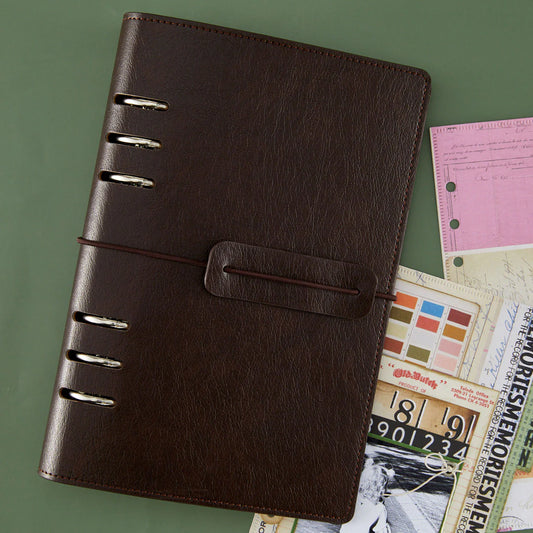 Brown leather notebook with metal rings on a green background