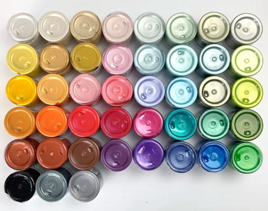 An array of colorful stencil butter jars in various colors, each with a labeled cap, arranged in rows on a white background.