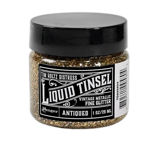 A jar of Ranger Tim Holtz Distress Liquid Tinsel Antiqued Vintage Metallic Fine Glitter, 1 oz / 29 ml, featuring a black lid and a black-and-white label, set against a plain white background.