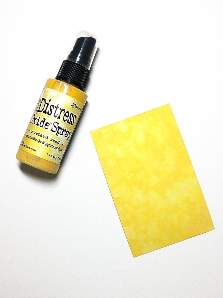 Distress oxide spray bottle with a mustard seed yellow sponge on a white background