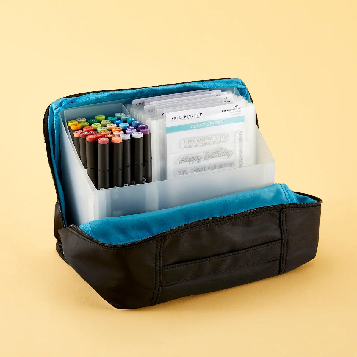 Black and teal carrying tote with zipper with markers and paper on a beige background