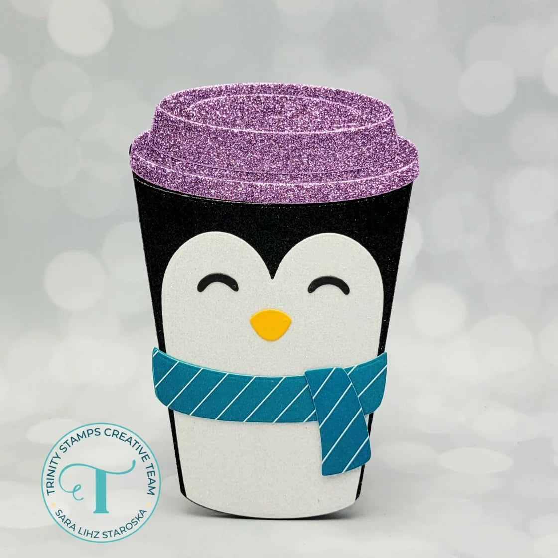 cute hot cup shaped card with a penguin as the decoration, the trinity stamps logo on a white bokah background