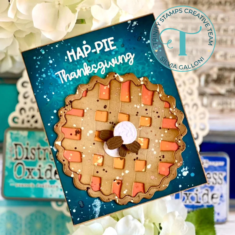 A handmade Thanksgiving-themed card featuring a detailed 3D maple pie design on a teal background with white text reading 'MAP-PIE Thanksgiving.' The card is styled with white flowers and other crafting supplies in the background.