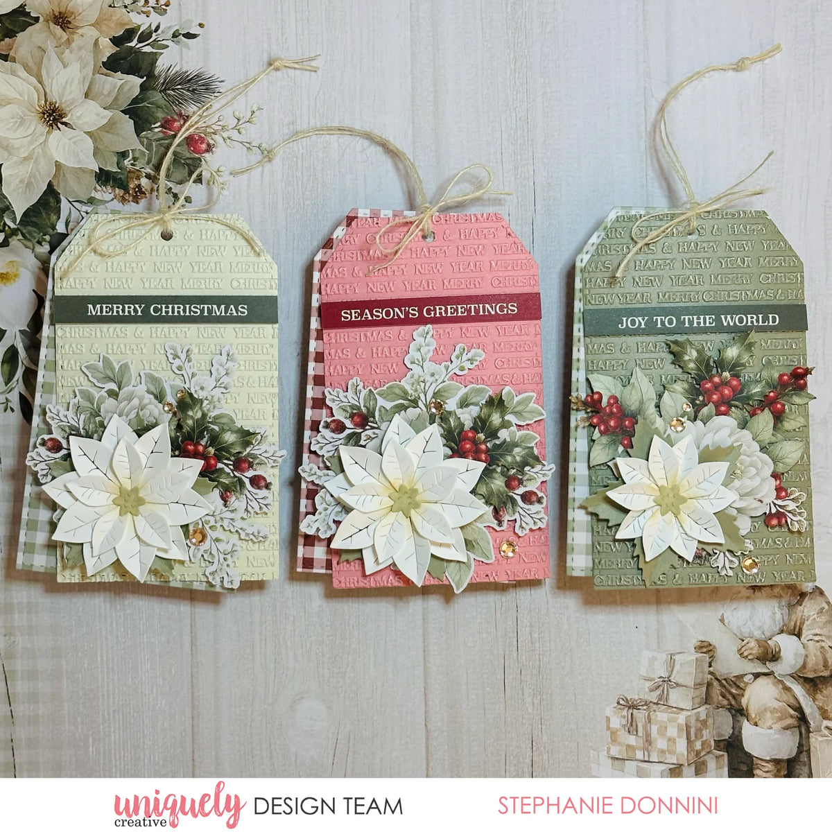 three holiday tags with pretty white flowers on a wood grain background